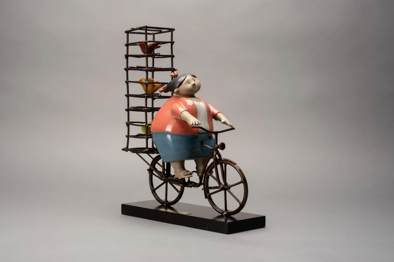Handmade ceramic sculpture by Rodo Padilla of a Mexican bird seller lady riding a bicycle with a birdcage – 7.1 x 2.4 x 5.9 inches – colorful folk art honoring everyday life and tradition.