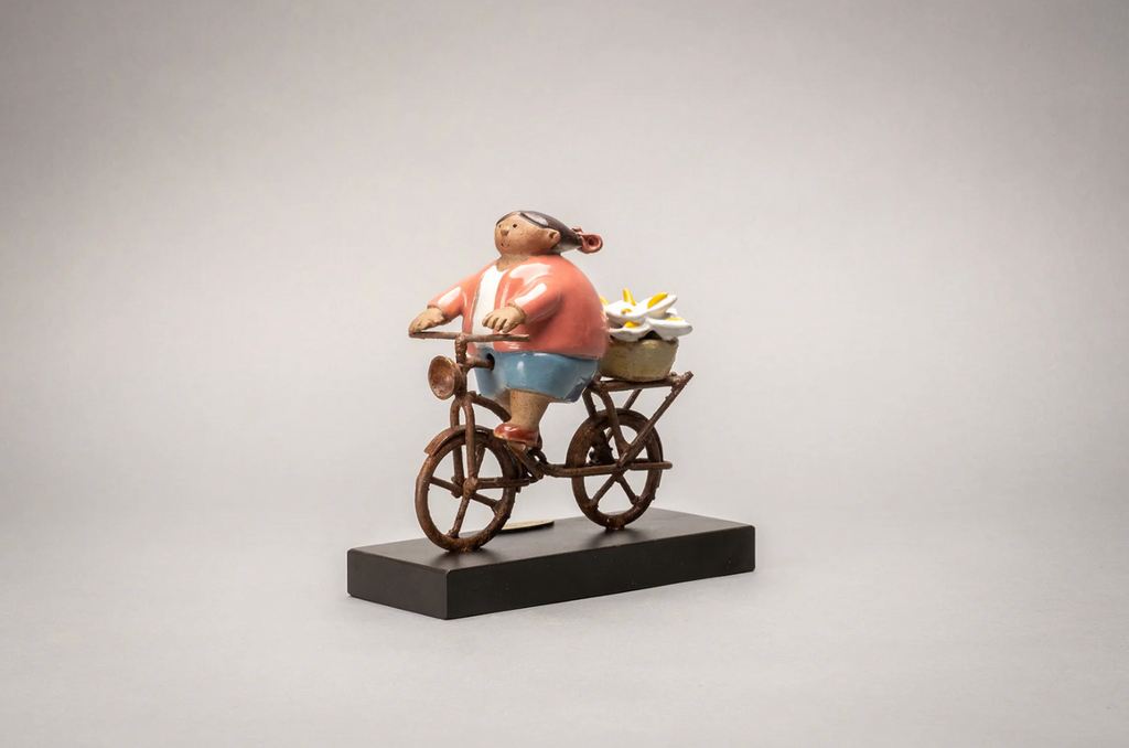 Florista Mujer en Bici handmade ceramic sculpture by Rodo Padilla featuring a flower vendor riding a bicycle, handcrafted and hand-painted in Mexico.
